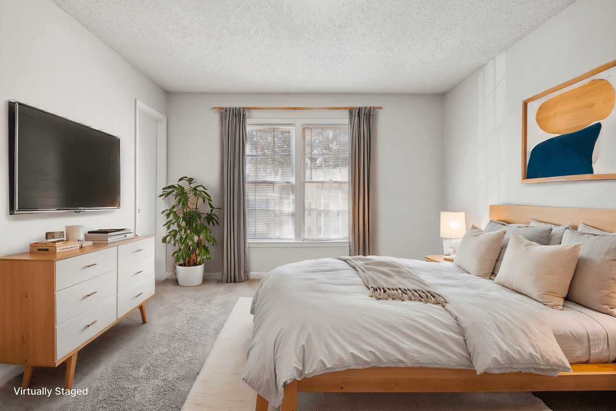 Virtually staged primary bedroom in a Quail Run apartment home